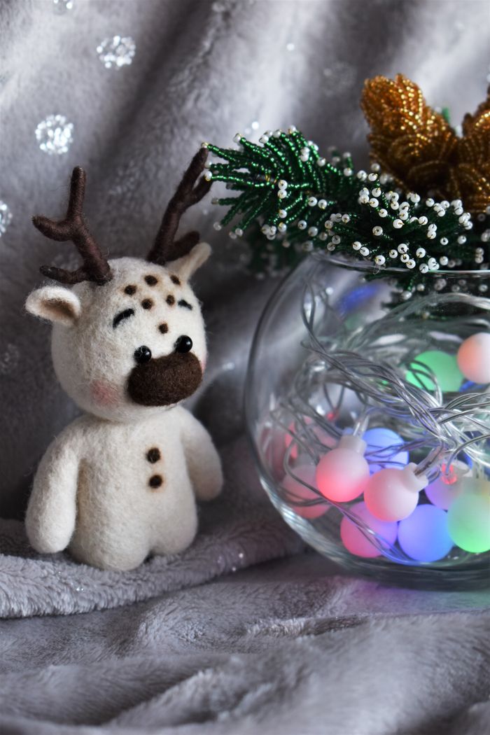 gallery-1 Charming reindeer toy with colorful Christmas lights in cozy holiday setting.