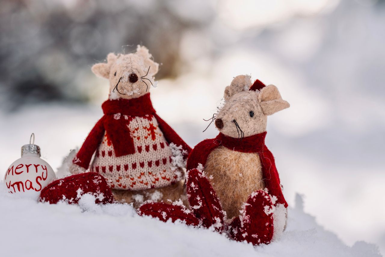 Two charming Christmas mouse figurines in winter snow with a festive ornament.