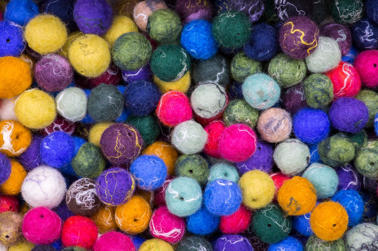 gallery-6 Vibrant collection of multicolored felt balls creating a rich textured background.