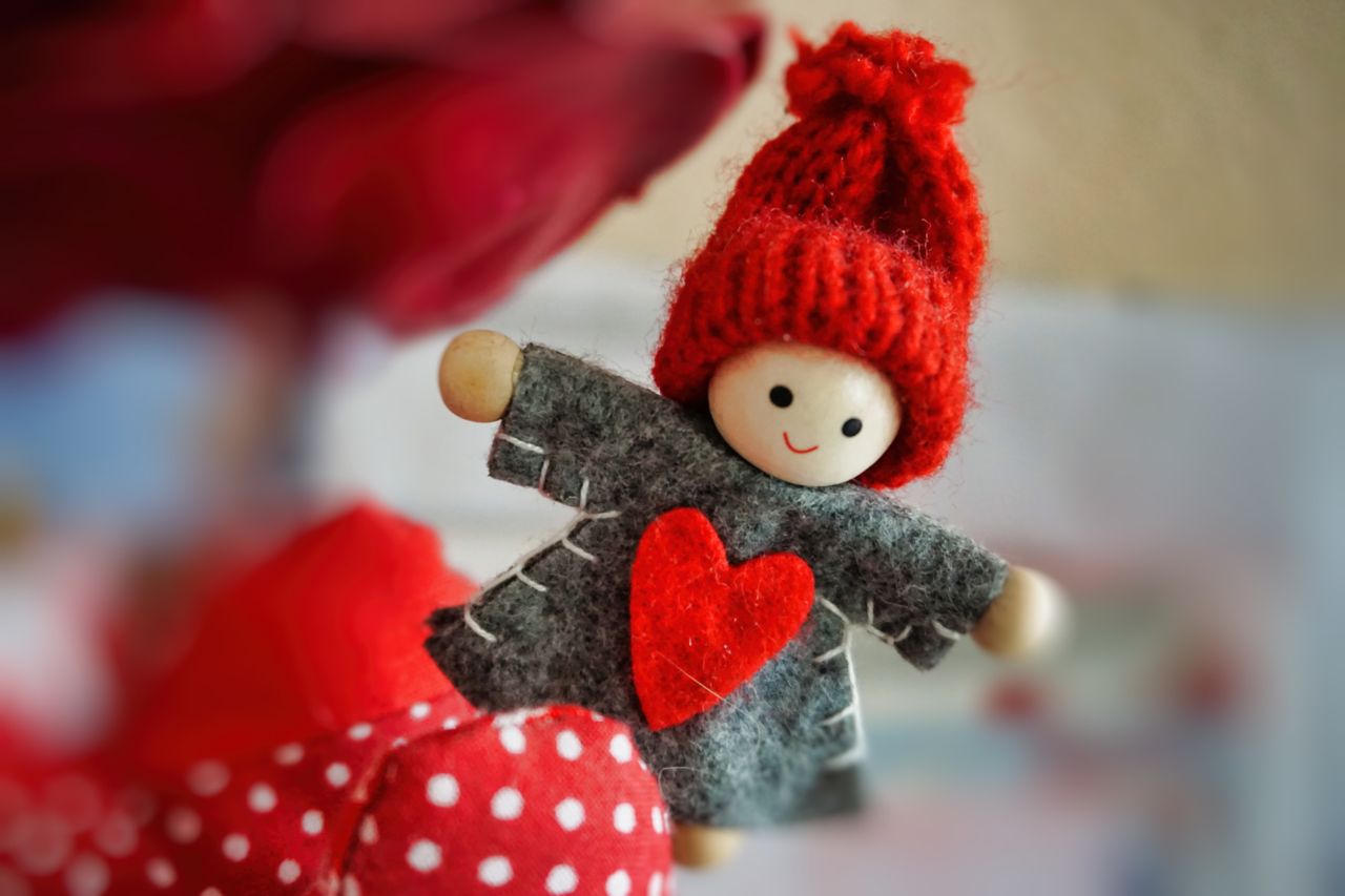Adorable handmade doll featuring a red knitted hat and felt heart design, perfect for crafting themes.